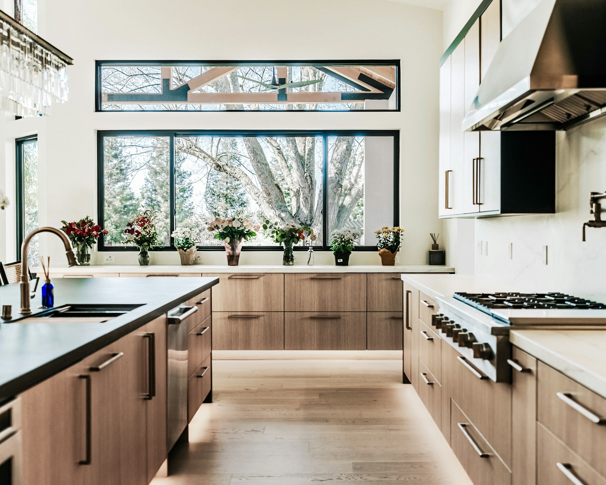 Contemporary kitchen with warm oak cabinets, white walls, and large windows; inspiration photography